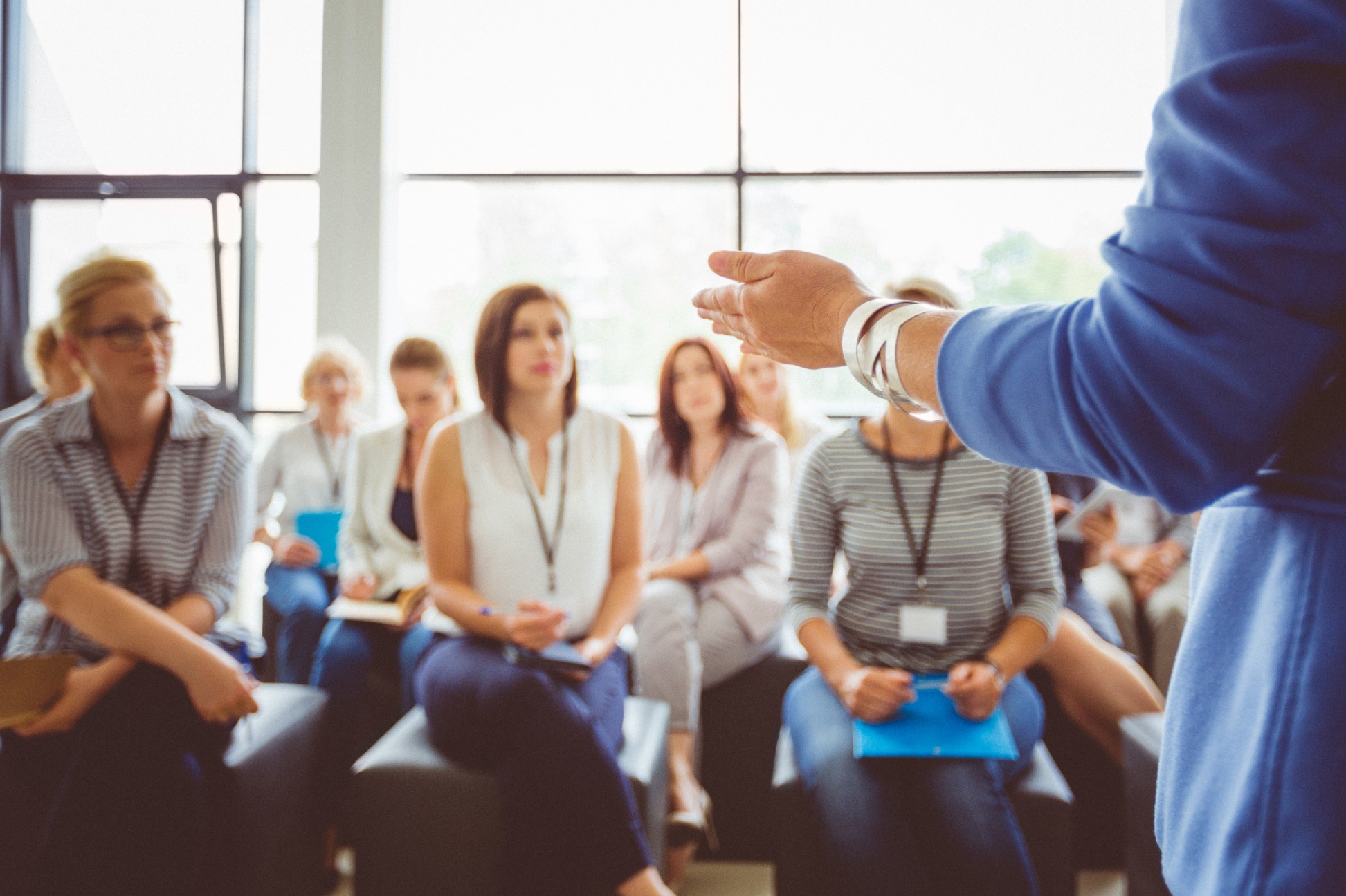adults sitting in a room listening to a speaker